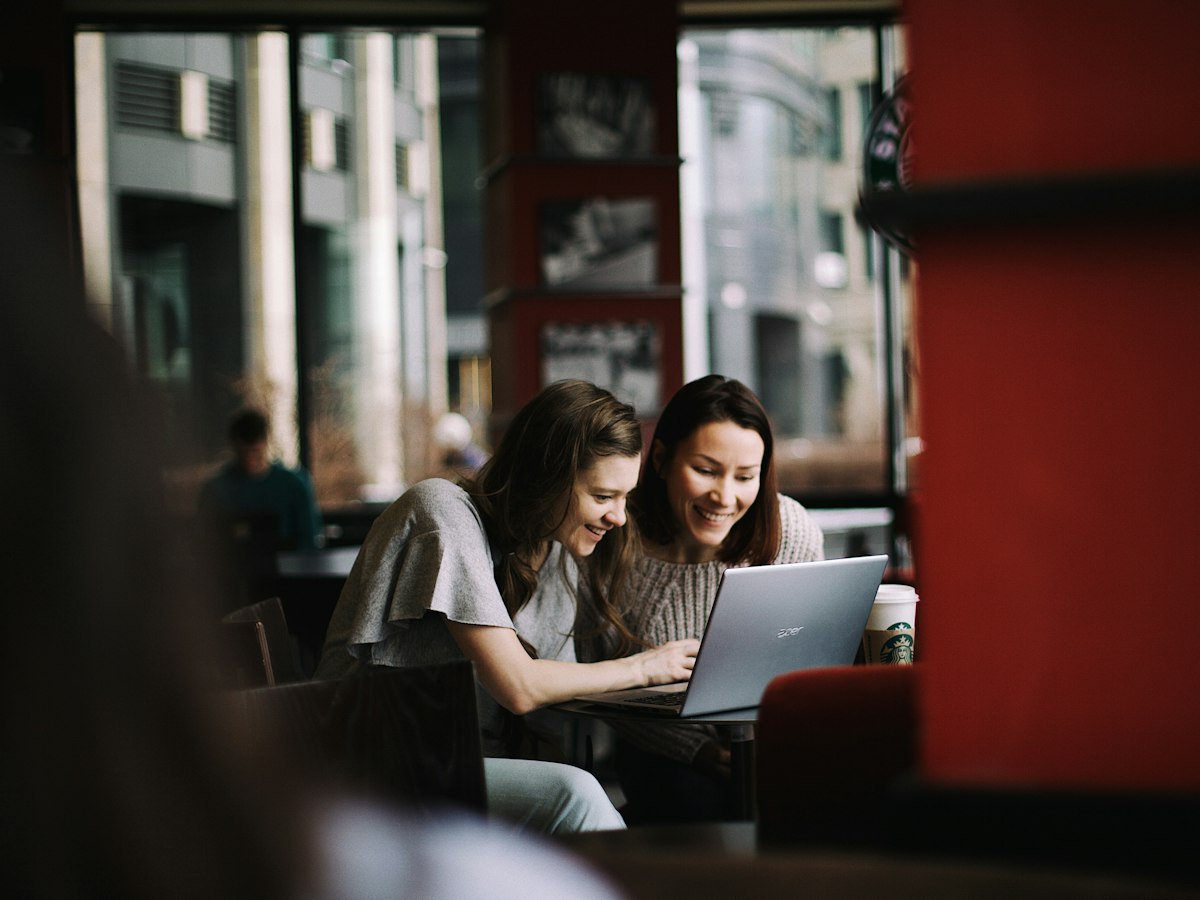 Two women talking over a laptop in a café