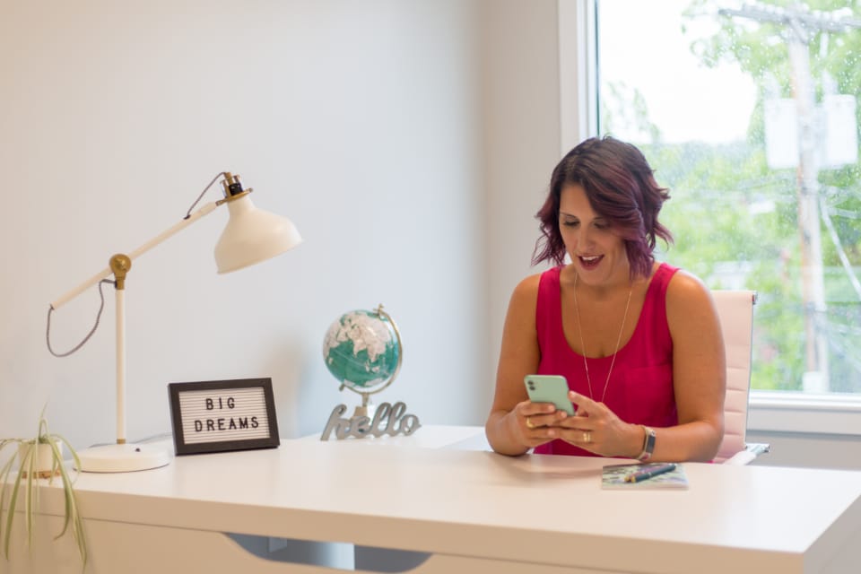 A woman at her desk checking her phone