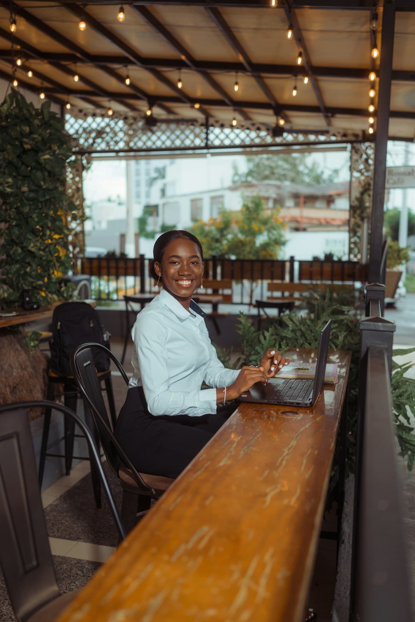 A smiling woman working on a laptop at a cafe table